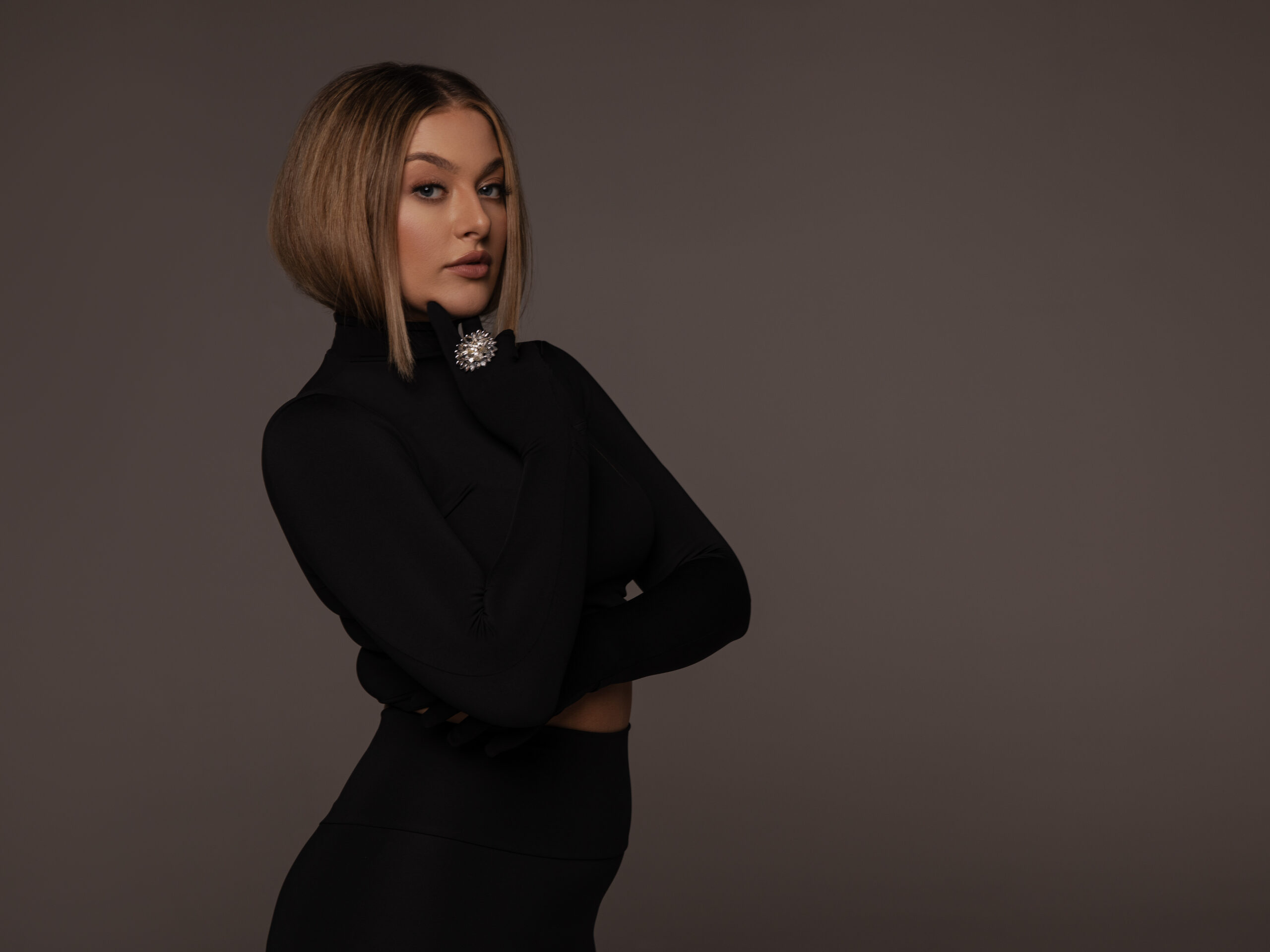 Kobieta w czarnym dopasowanym zestawie z ozdobną broszką – elegancka stylizacja casual